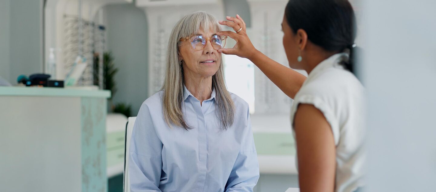 femme de 50 ans chez l'opticien qui essaie une paire de lunette