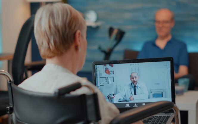 femme en fauteuil roulant qui est en ligne avec un medecin sur l'ordinateur