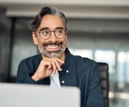 homme à lunette qui sourit devant ordinateur