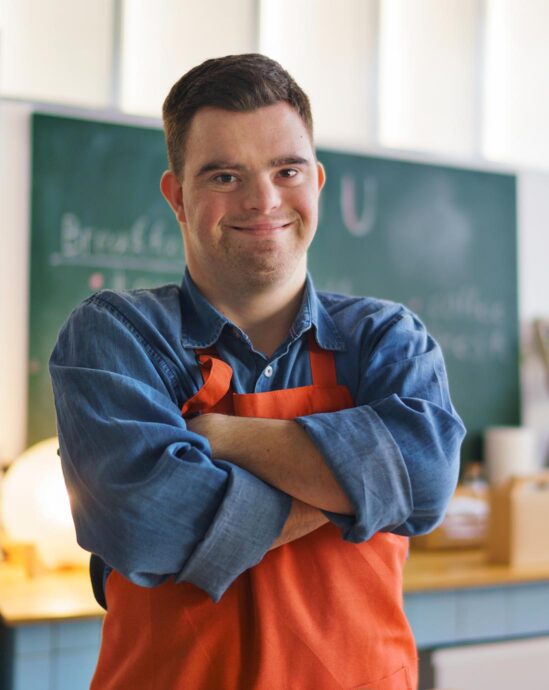 Jeune garçon joyeux sur le syndrome de Down travaillant dans un restaurant à emporter