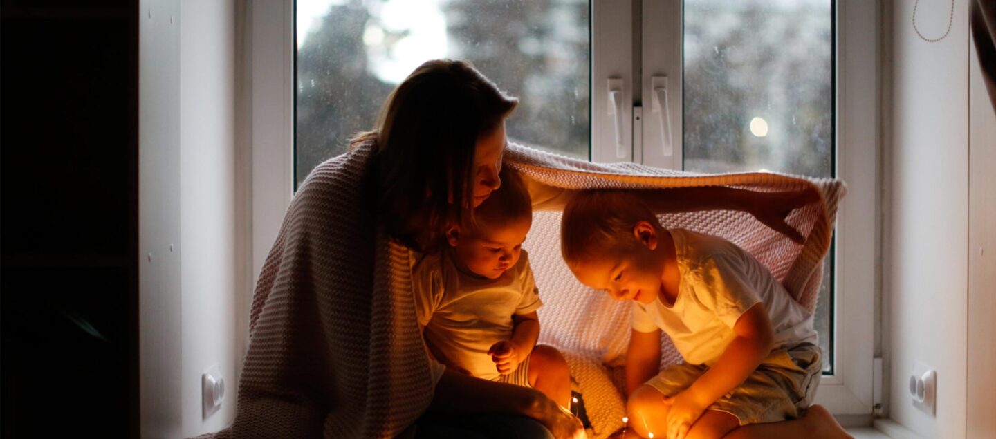 femme avec deux enfants sous un plaid