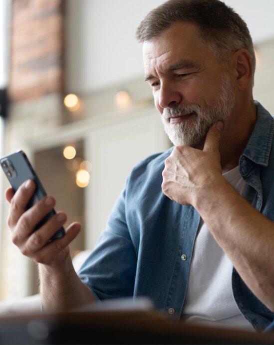 homme de 50 ans qui regarde son téléphone