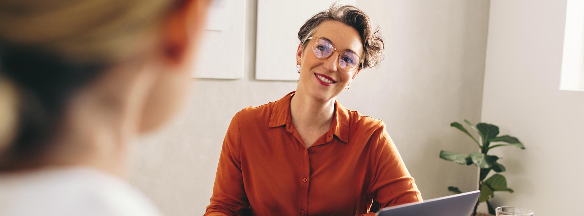 femme avec un chemisier rouge qui ecoute une collaboratrice