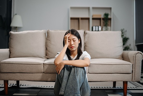 une femme assise au sol, prise par l'anxiété