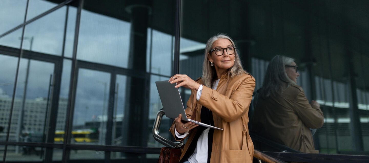 femme d'affaire avec son ordinateur devant son batiment