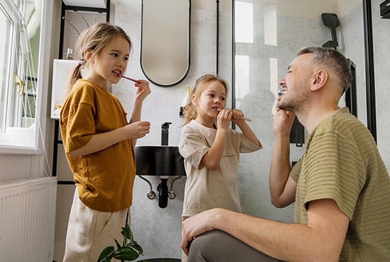 un père et ses deux filles entrain de se brosser les dents